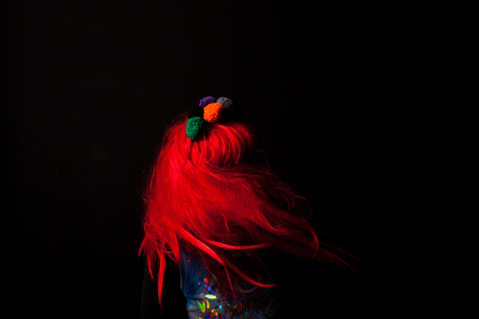 A black background, a body with bright red hair and a costume whirls